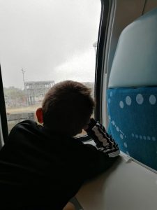 Un enfant regarde rêveusement à travers la fenêtre du train alors qu'il pleut