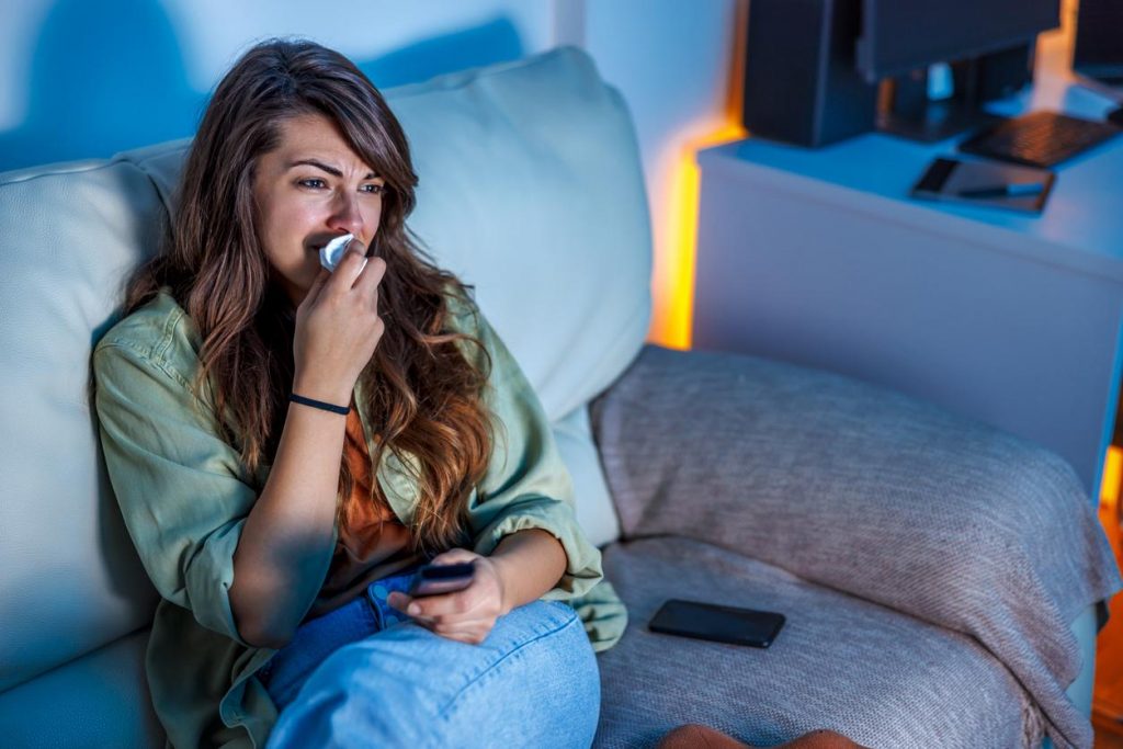 Une femme pleure devant un film, contexte émotionnel chargé